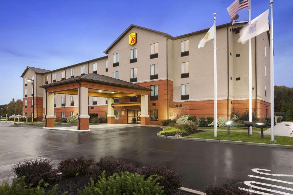 ein Hotel mit Flaggen vor einem Parkplatz in der Unterkunft Super 8 by Wyndham Pennsville/Wilmington in Pennsville