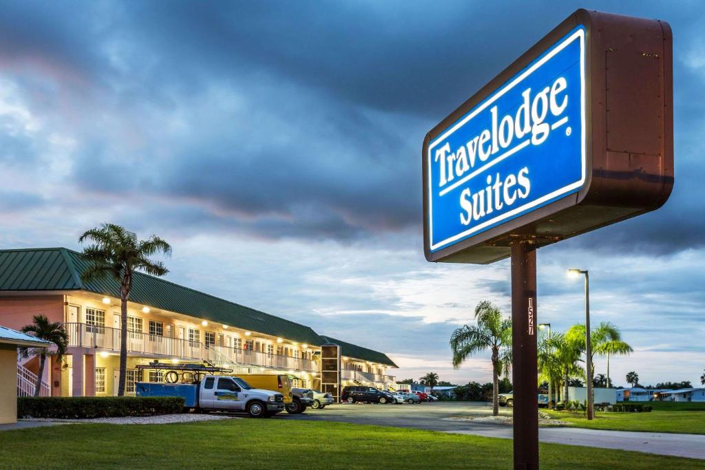a sign in front of a hotel with a building at Travelodge Suites by Wyndham Lake Okeechobee in Okeechobee