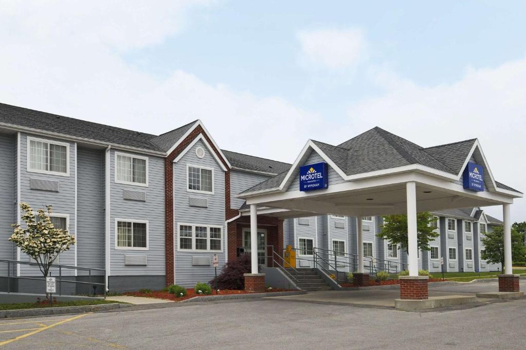 a row of buildings with a parking lot in front at Microtel Inn & Suites by Wyndham Syracuse Baldwinsville in Baldwinsville