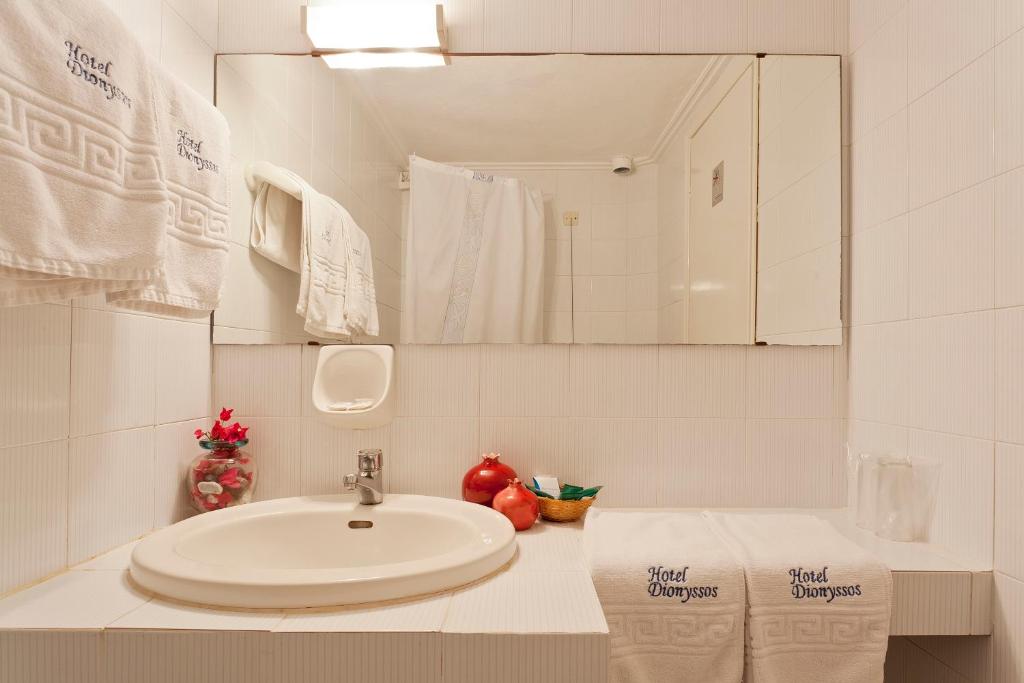 a white bathroom with a sink and a mirror at Dionyssos in Skopelos Town