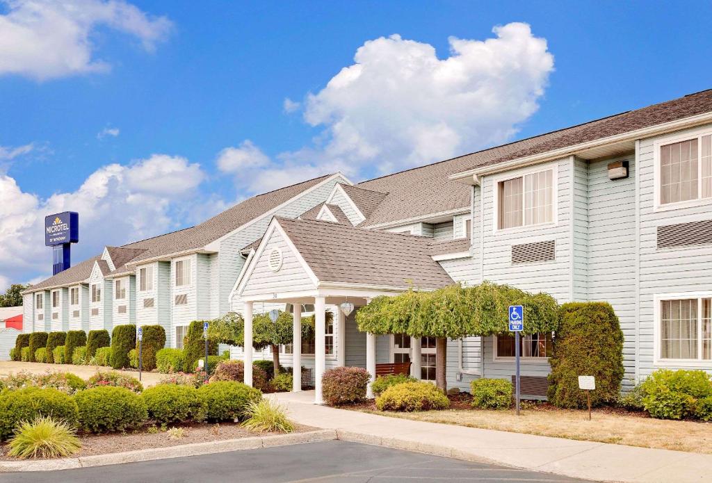 a large white building with bushes in front of it at Microtel Inn & Suites by Wyndham Wellsville in Wellsville