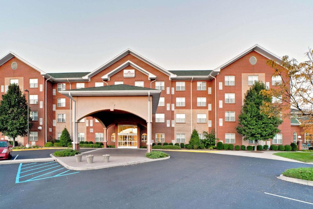 a large red brick building with a parking lot at Hawthorn Suites by Wyndham Louisville East in Louisville