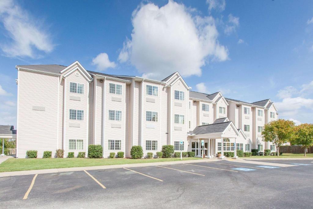 a large white building with a parking lot at Microtel Inn by Wyndham Rogers in Rogers