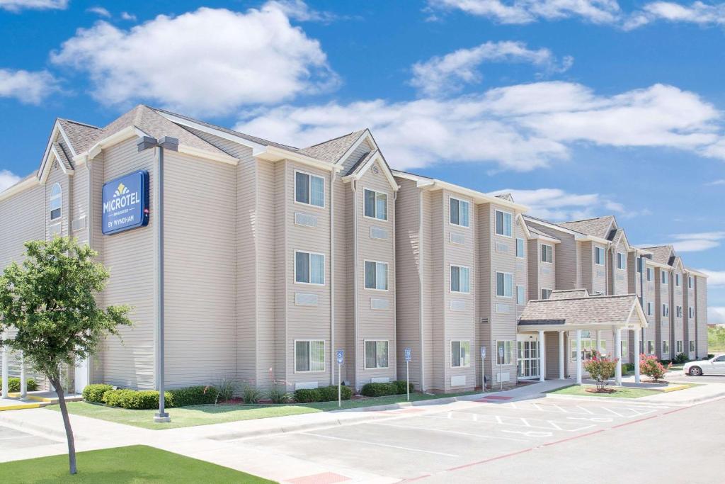 a large apartment building with a blue sign on it at Microtel Inn and Suites San Angelo in San Angelo