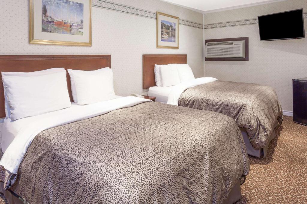 ein Hotelzimmer mit 2 Betten und einem Flachbild-TV in der Unterkunft Knights Inn Kingston in Kingston