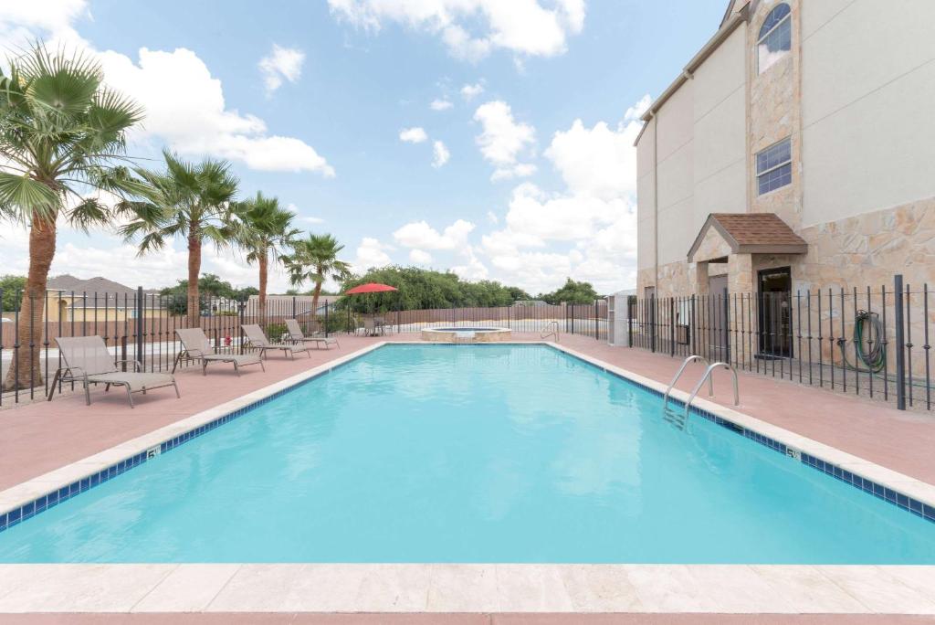 a swimming pool at a resort with palm trees and a building at Microtel Inn and Suites Eagle Pass in Eagle Pass
