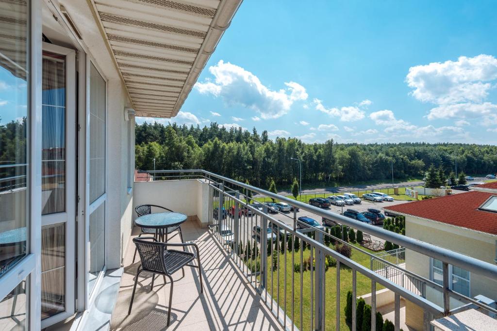 a balcony with two chairs and a view of a parking lot at Apartament Osiedle Bałtyk in Grzybowo