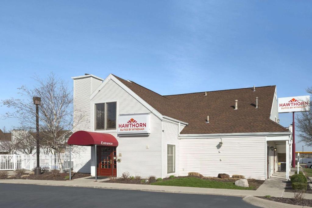 a white building with a red awning on a street at Hawthorn Suites - Fort Wayne in Fort Wayne