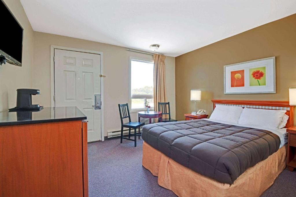 a hotel room with a bed and a desk at Howard Johnson by Wyndham Lindsay in Lindsay