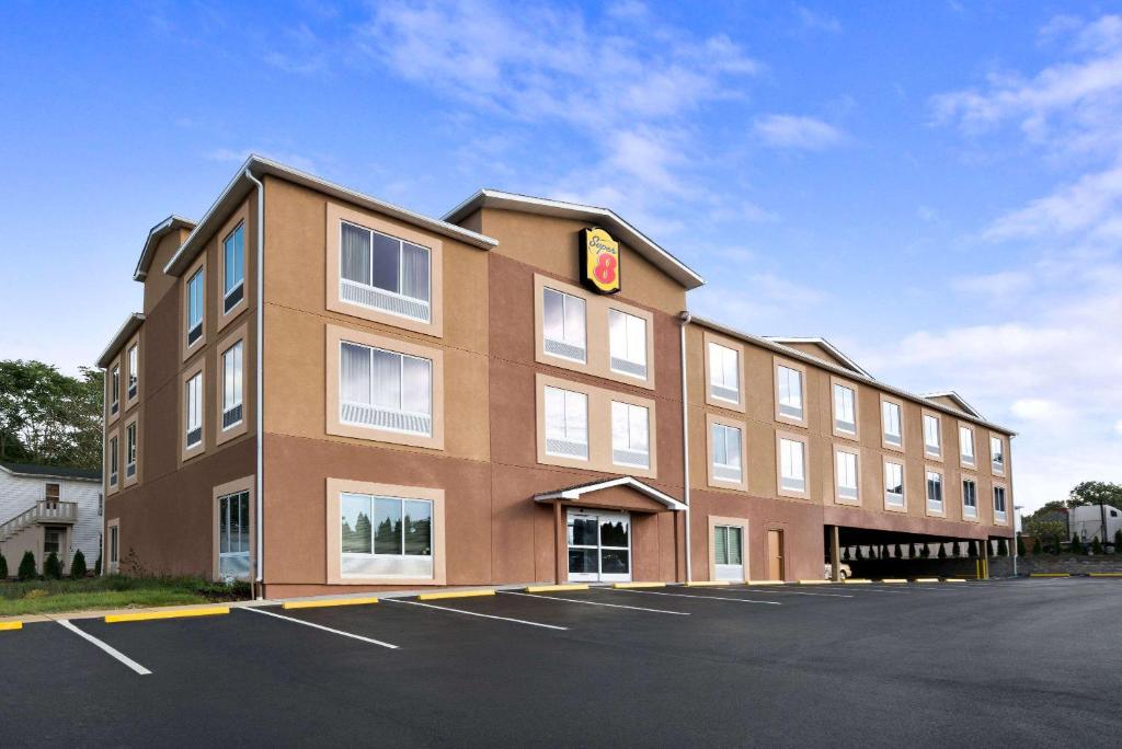 a large building with a parking lot in front of it at Super 8 by Wyndham Hershey Chocolate Avenue in Hershey