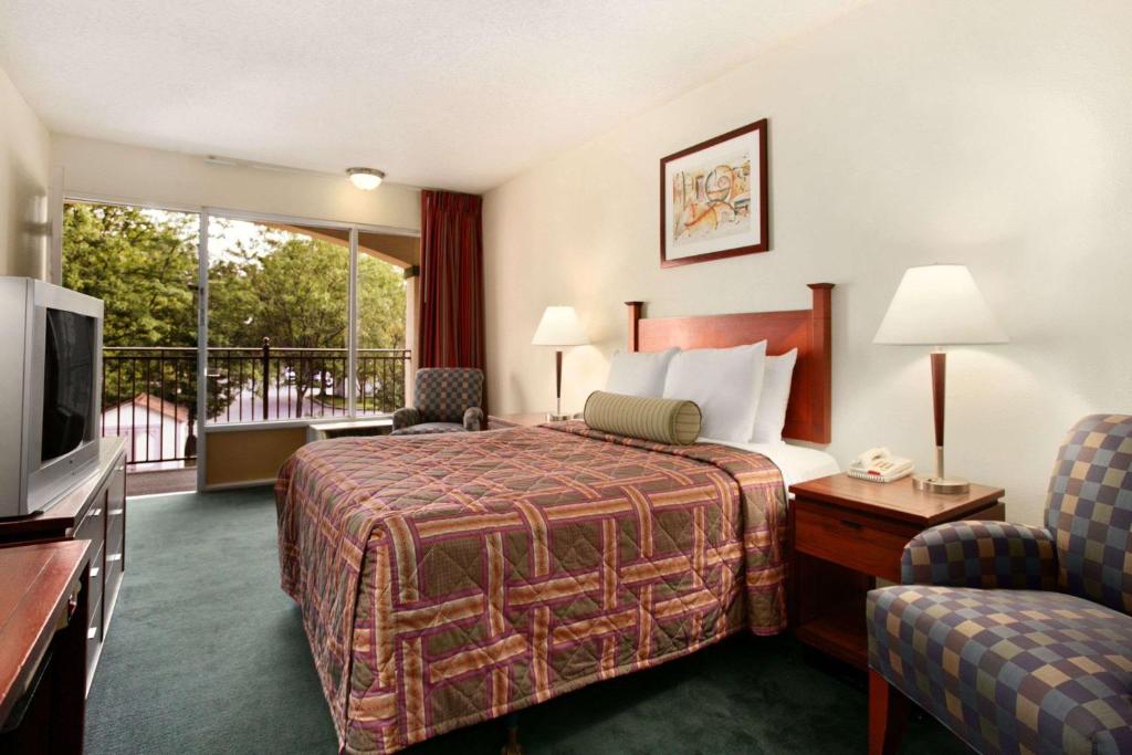 a hotel room with a bed and a balcony at Travelodge by Wyndham Waukegan Gurnee in Waukegan