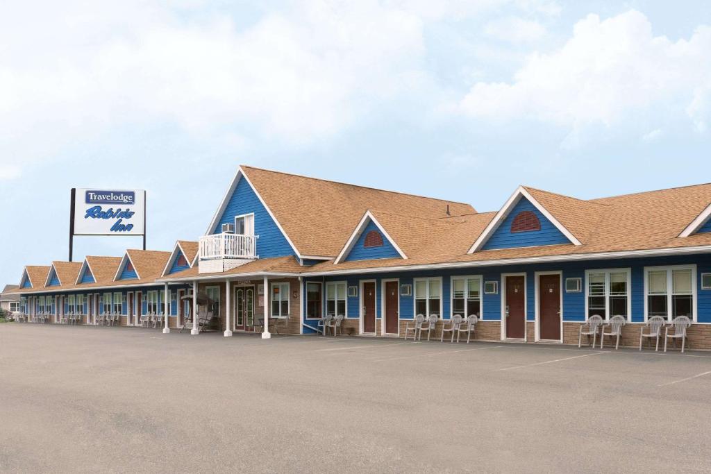 a row of buildings with chairs in a parking lot at Travelodge by Wyndham Fredericton in Fredericton