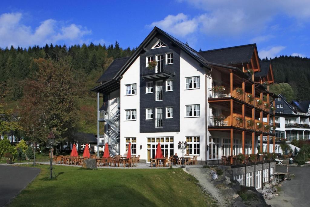 a large black and white building with tables and chairs at Land- und Kurhotel Tommes in Schmallenberg