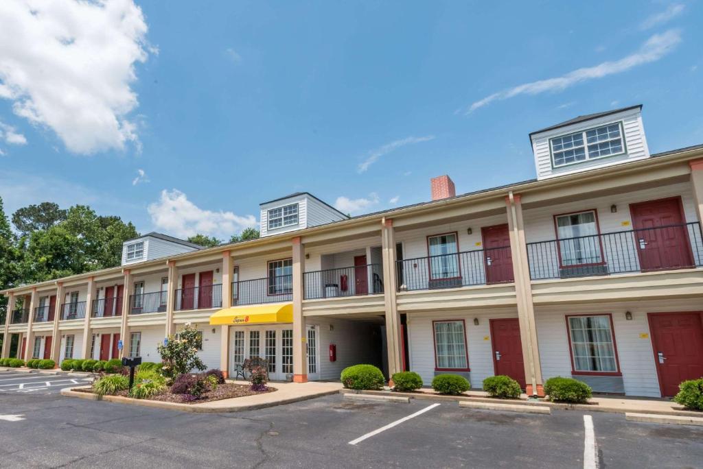 a large white building with red windows and a parking lot at Super 8 by Wyndham Alexander City in Alexander City