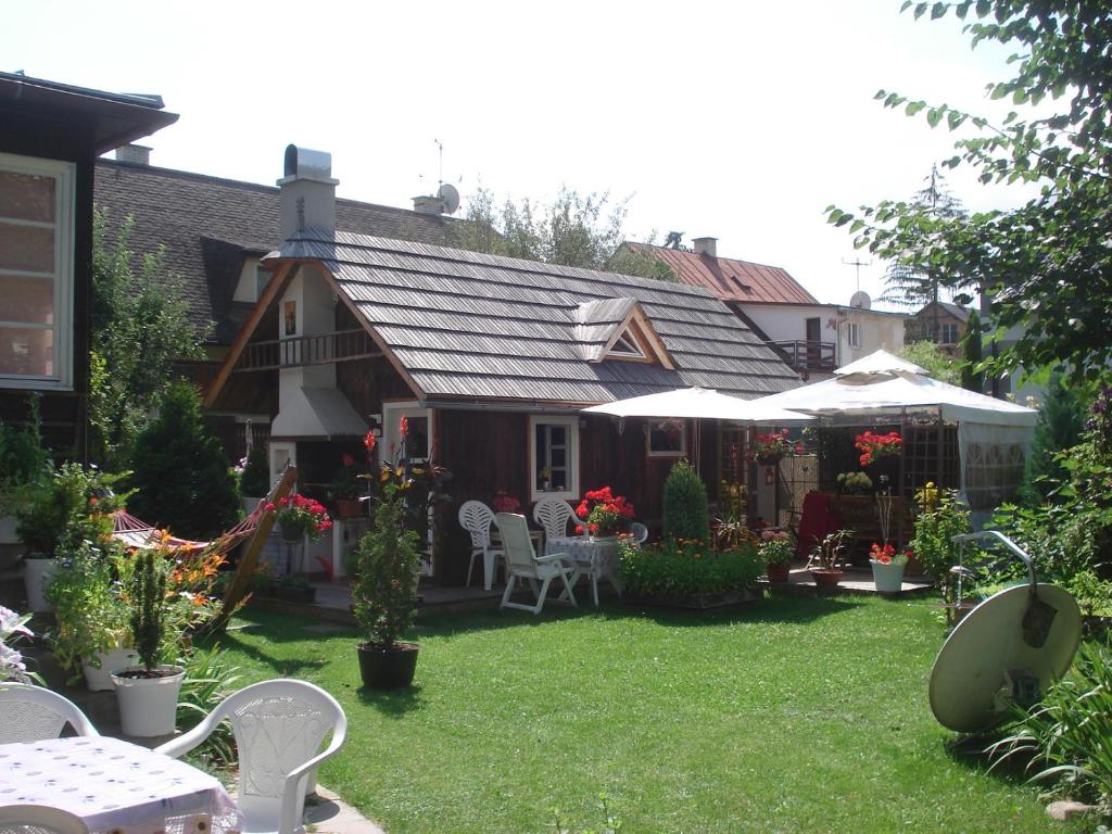 uma casa com um quintal com cadeiras brancas e flores em chatka em Rajecké Teplice