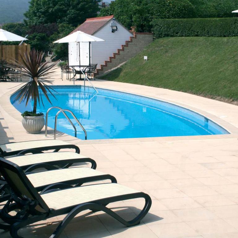 um grupo de espreguiçadeiras ao lado de uma piscina em Hydro Hotel em Eastbourne