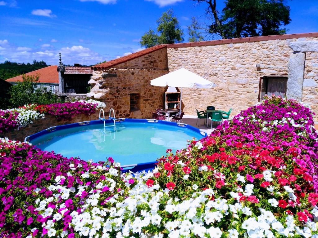 una piscina en un jardín con flores en REMANSO DE TRASFONTAO "Casa do Campo" en Silleda