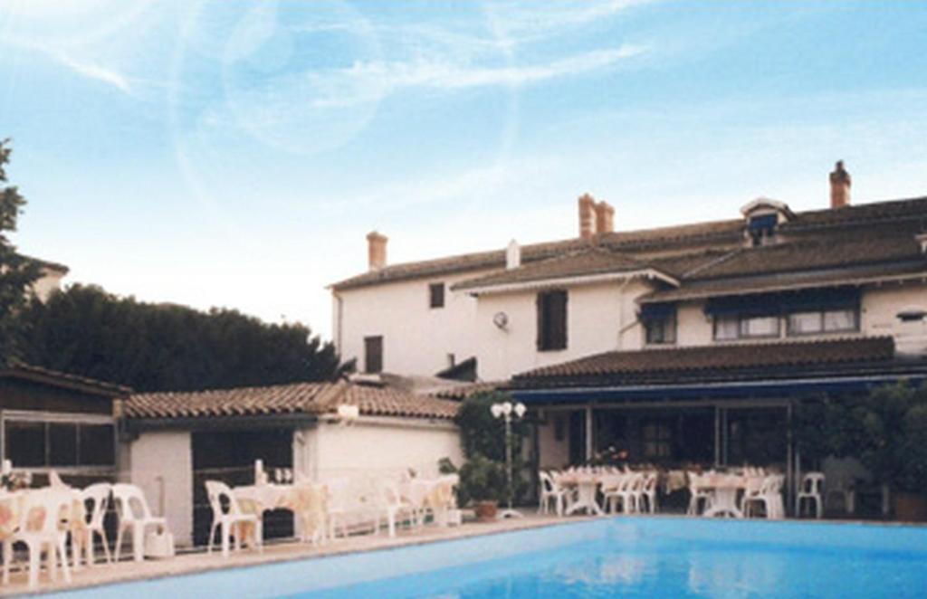 una casa con piscina y sillas blancas en La Maison Blanche en Romanèche-Thorins