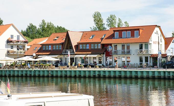 a building with tables and chairs next to the water at Hotel zur Brücke in Greifswald