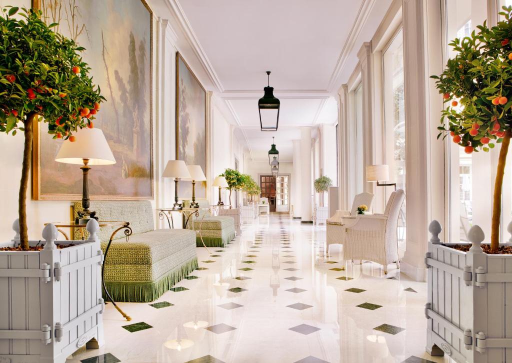 un couloir d'un hôtel avec des sols et des plantes blancs dans l'établissement Le Bristol Paris - an Oetker Collection Hotel, à Paris