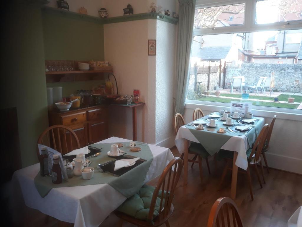uma sala de jantar com duas mesas e uma janela em Glenavon Guest House em Llandudno