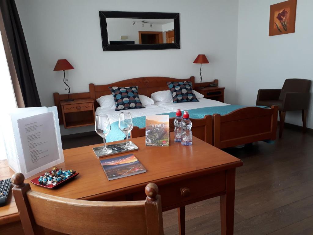 Ein Zimmer mit einem Bett und einem Holztisch mit einem sidx sidx in der Unterkunft Hôtel de Fully in Fully