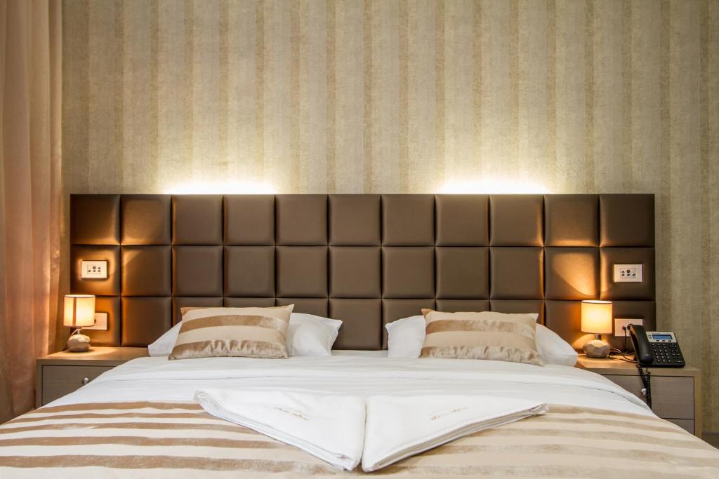 a bedroom with a large bed with a large headboard at Royal Airport Hotel in Velika Gorica