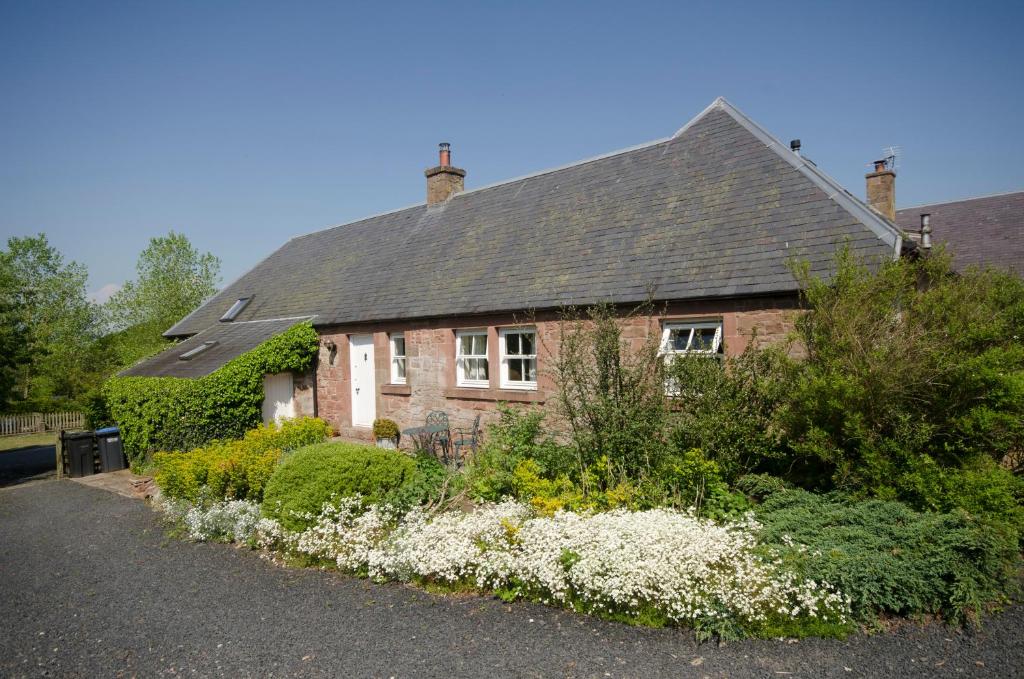 una casa con un jardín delante de ella en The Steadings Cottage en Chesters
