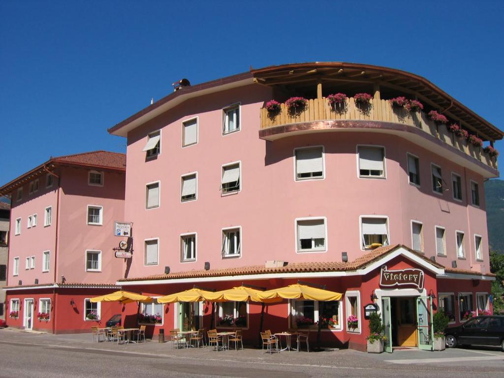 un edificio rosa con tavoli e sedie di fronte di Hotel Victory a Taio