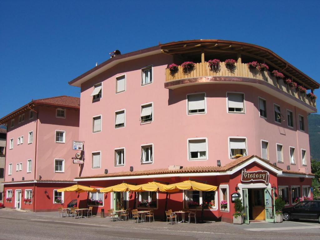 a pink building with tables and chairs in front of it at Hotel Victory in Taio
