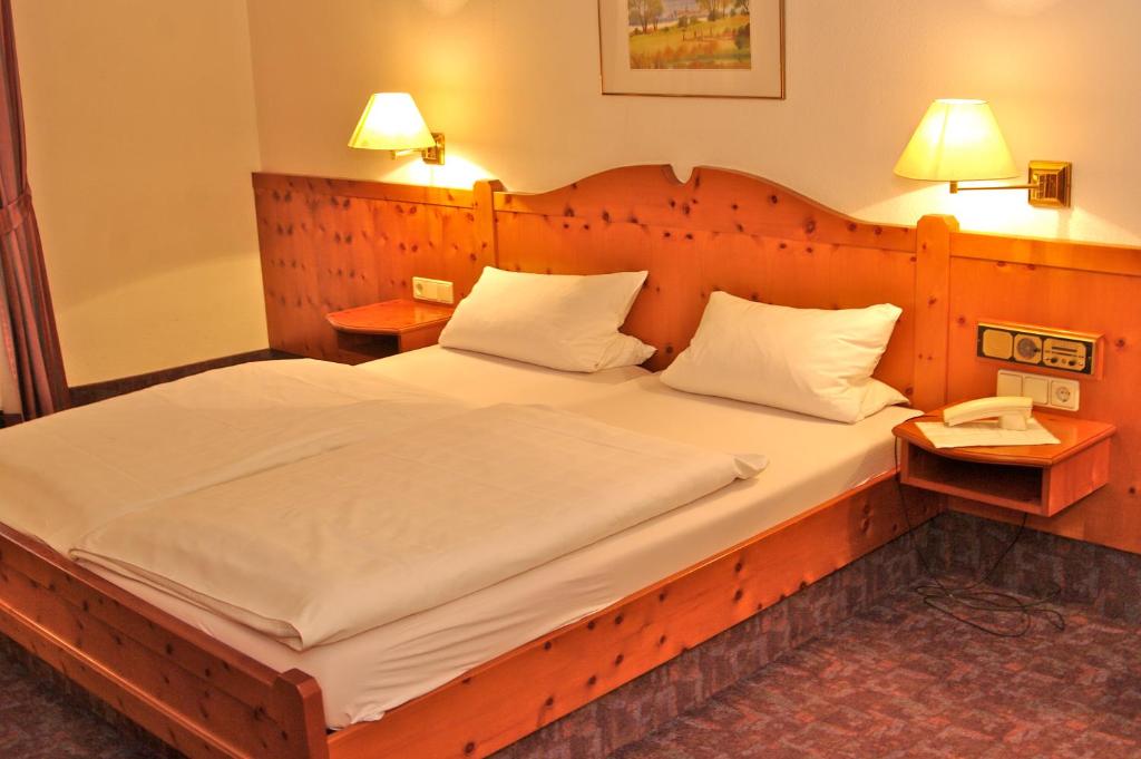 a bedroom with a large bed with a wooden headboard at Gasthof zum Kauzen in Ochsenfurt