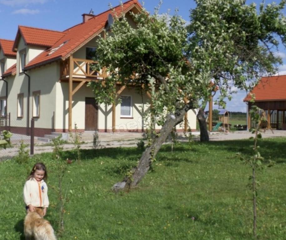 ミコワイキにあるEko Zagroda Bocianie Gniazdoの犬と芝生に立つ少女