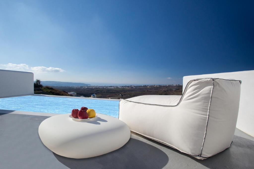 een witte stoel op een tafel naast een zwembad bij Alunia Incognito Suites - Adults Only in Pirgos