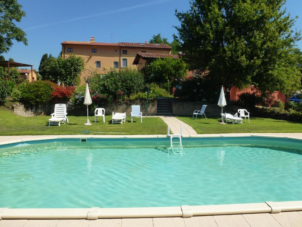 a large swimming pool with chairs and umbrellas at Agriturismo Poggio al Tesoro in Crespina