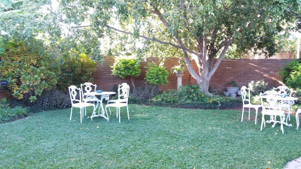 un grupo de sillas y mesas blancas en un patio en HH 820 Accomodation en Grootfontein