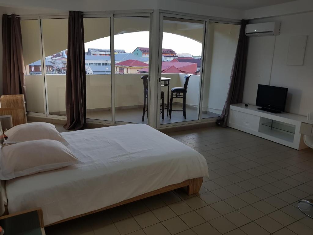 a bedroom with a bed and a balcony with a television at Hello Guyane 1 - Appartement de Luxe, 5 étoiles in Cayenne