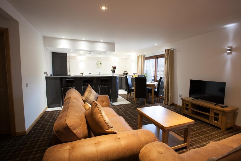 Una sala de estar con un sofá y una cocina. en Tower Ridge Apartments, en Fort William