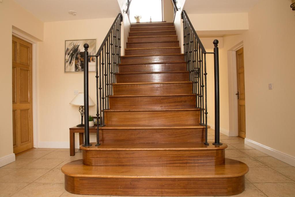 a staircase in a home with wooden floors and black railings at On Lakeshore with Horses, Jetty & Games Room in Boyle
