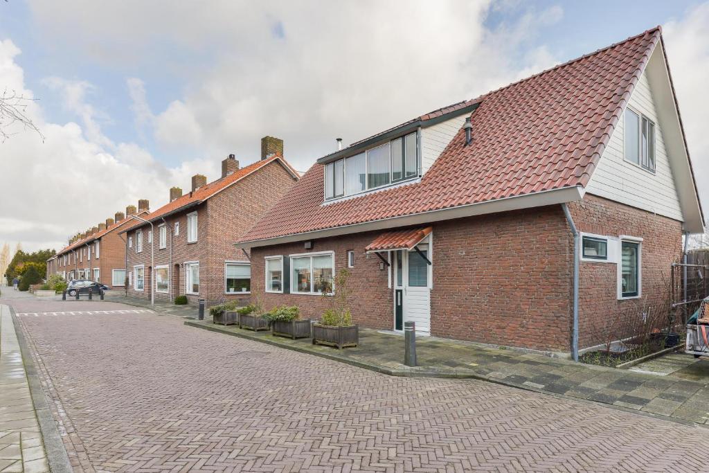 a brick building with a red roof on a street at Spacious Family Home Halfweg in Halfweg