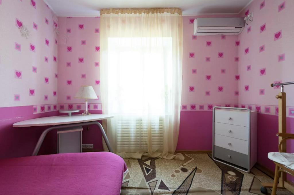 Habitación de color rosa con ventana y escritorio. en Guest House on Kaldaiakova 38, en Almaty