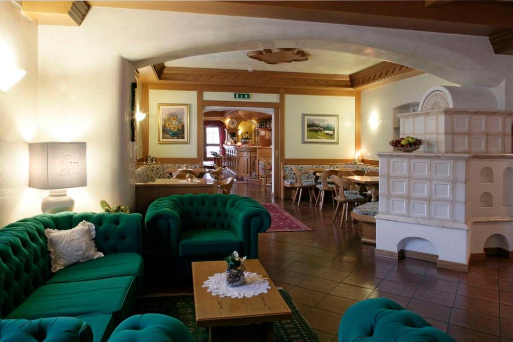 a living room with green couches and a fireplace at Hotel Al Polo in Ziano di Fiemme