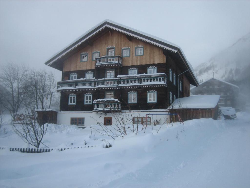 ein großes Holzgebäude mit Schnee auf dem Boden in der Unterkunft Haus Ursula in Kals am Großglockner