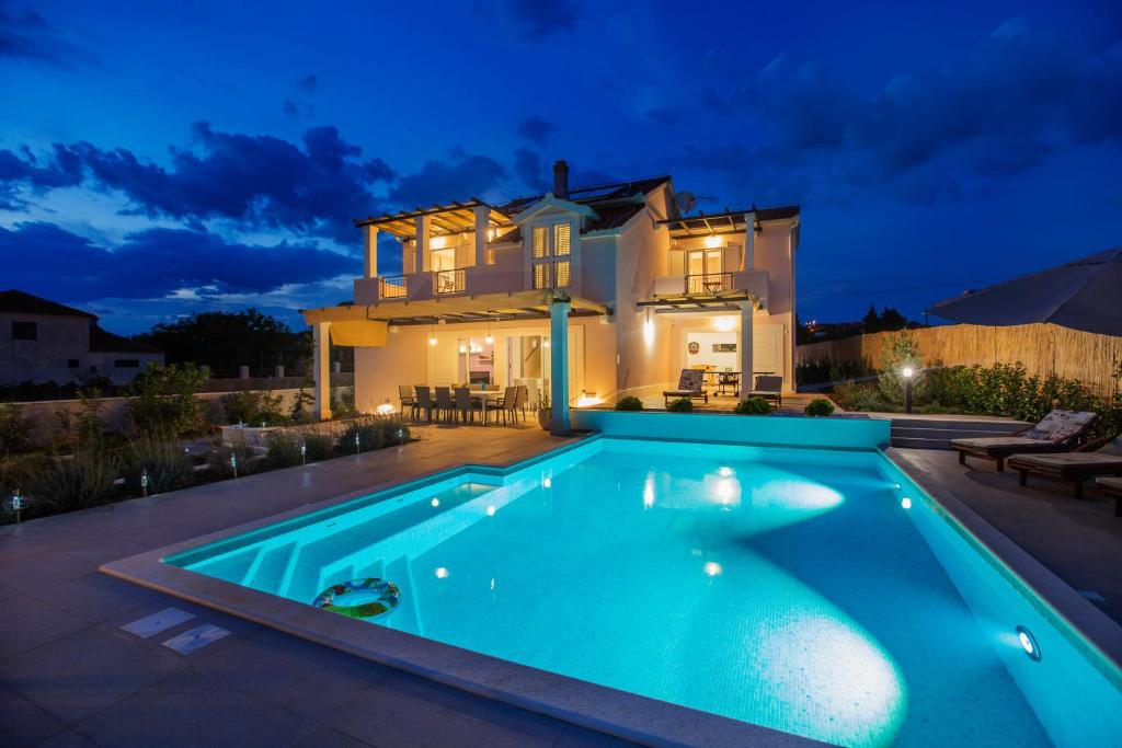 a swimming pool in front of a house at night at Villa Giove in Grohote