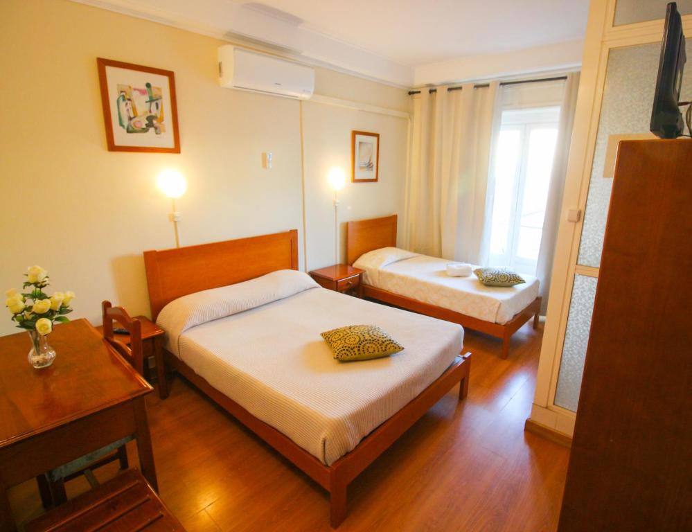 een hotelkamer met 2 bedden en een raam bij Residencial Lord in Lissabon