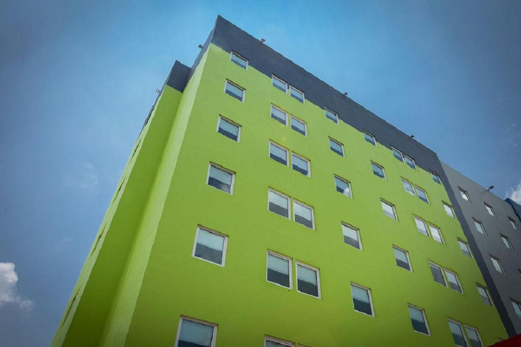 a tall green building with a blue sky in the background at SR Hotel in Guadalajara