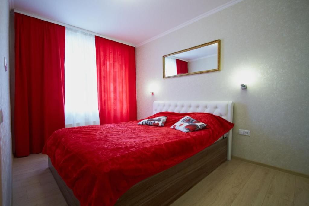 a bedroom with a bed with red sheets and a window at Vilenskaya 19 in Maladzyechna