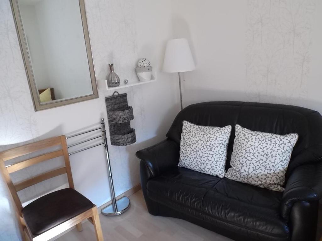 un sofá de cuero negro y una silla en una habitación en Zimmer Schmitz, en Anschau