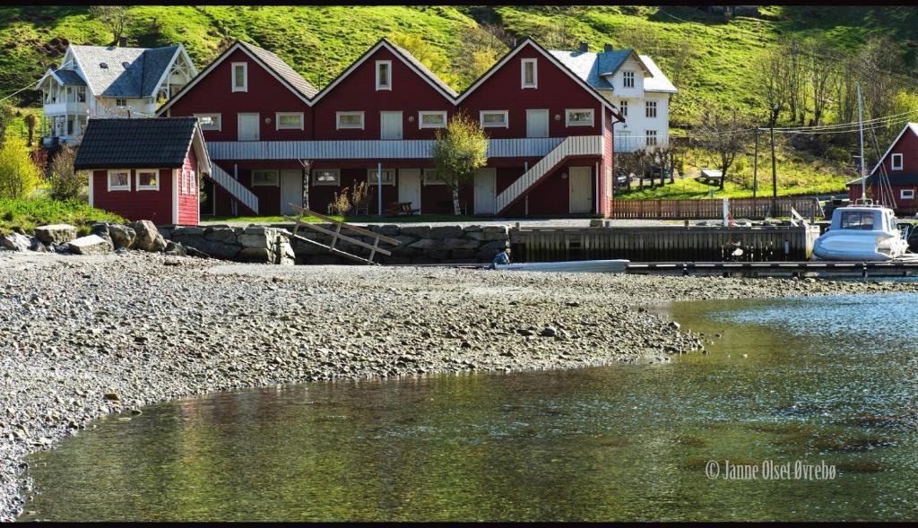 a large red house next to a body of water at Grandane Feriehus in Stongfjorden