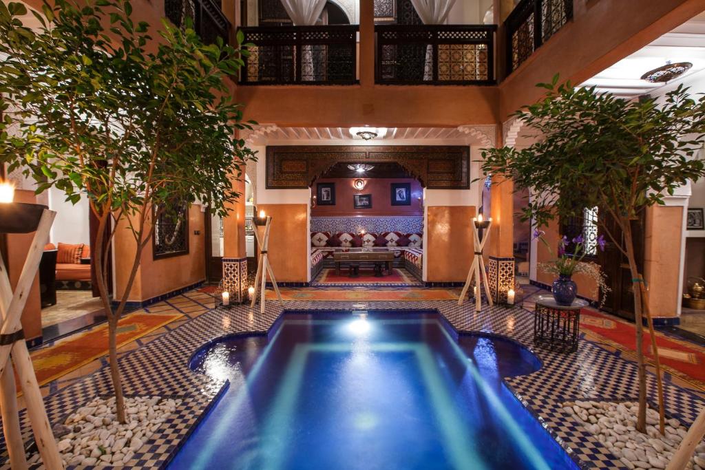 a pool in the middle of a room with trees at Riad Alaka in Marrakesh