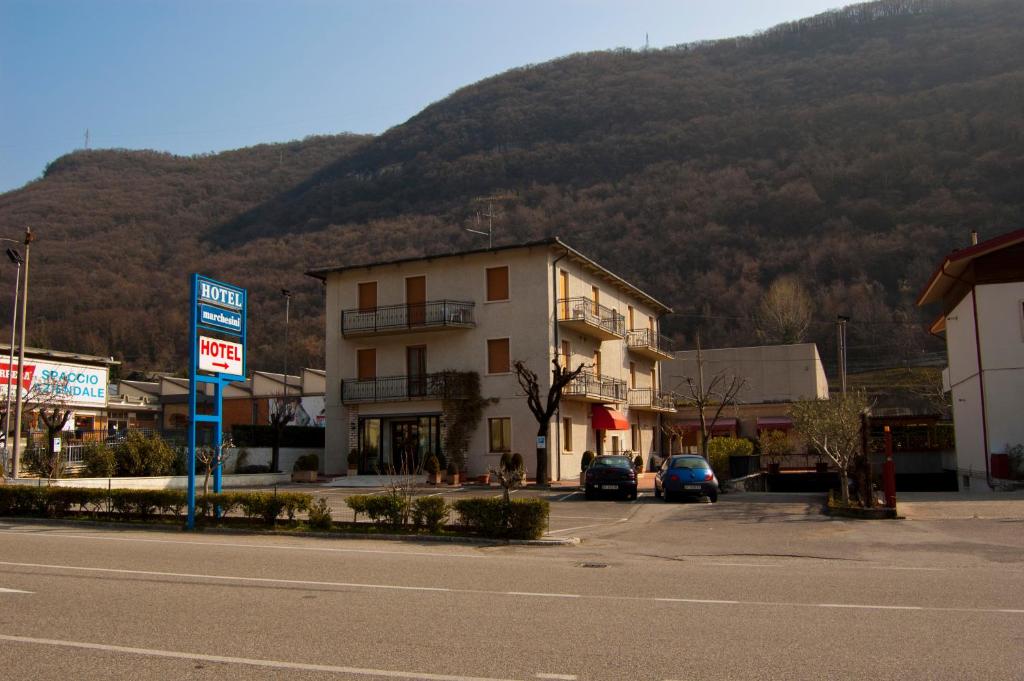 um edifício ao lado de uma rua com uma montanha em Hotel Marchesini em Grezzana